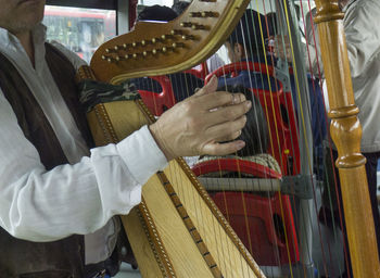 Midsection of musician playing harp in bus