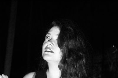 Young woman looking away standing outdoors at night