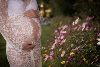 Midsection of woman standing by flowering plants