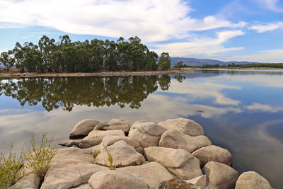 Rocks by lake against sky