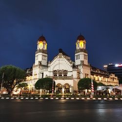 Illuminated building against blue sky at night