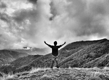 Rear view of man standing on mountain against sky