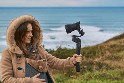 Full length of woman photographing sea during winter