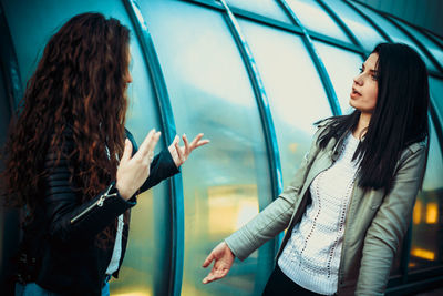 Female friends talking while standing on street in city