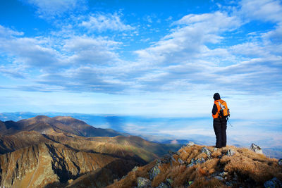 Rear view of man standing on mountain against sky