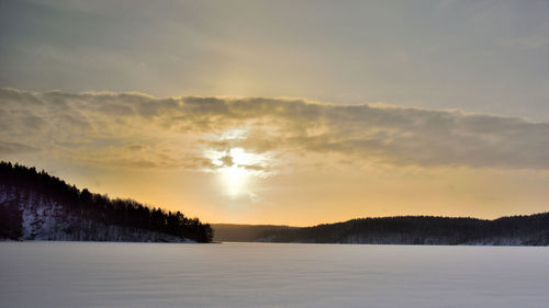 Scenic view of snow covered landscape against sky during sunset