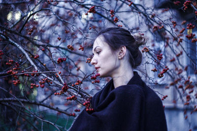 Young woman standing by tree in forest