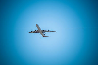 Low angle view of airplane against clear blue sky