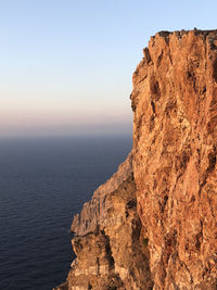 Rock formations by sea against clear sky