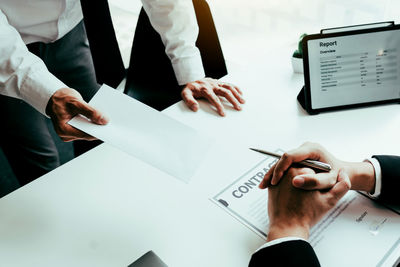 Midsection of man holding paper with text on table