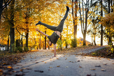 Man walking on road amidst trees during autumn