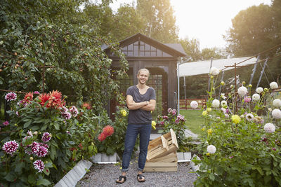 Full length portrait of gardener standing arms crossed in yard