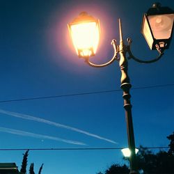 Low angle view of illuminated street light against blue sky