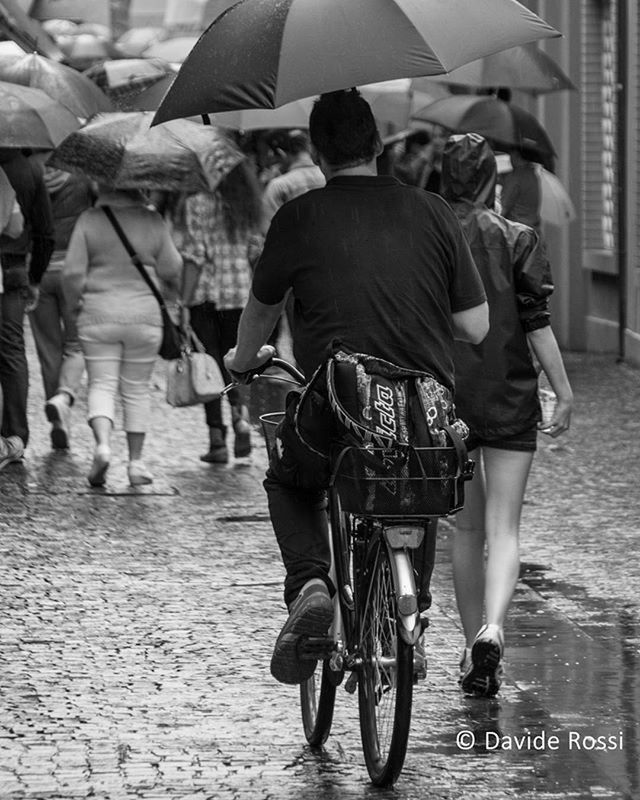 men, lifestyles, street, full length, person, leisure activity, casual clothing, walking, large group of people, rear view, togetherness, city life, bicycle, standing, outdoors, sidewalk, focus on foreground, city, day