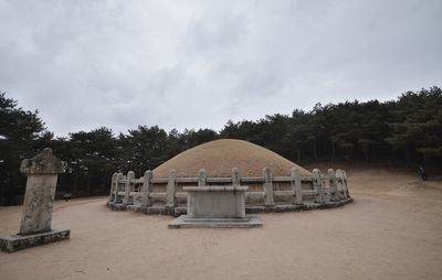 Built structure on field by trees against sky