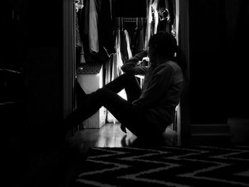 Full length of person sitting on doorway in darkroom