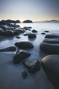 Rocks on beach against sky during sunset