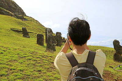 Traveler taking pictures of abandoned moai statues on rano raraku volcano on easter island of chile