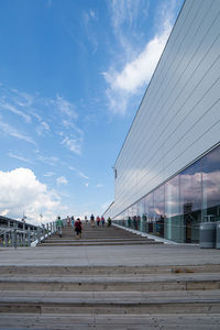 People walking on bridge in city against sky