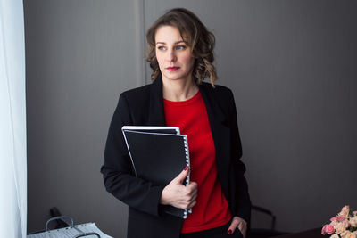 Young business woman or manager standing at workplace with folders