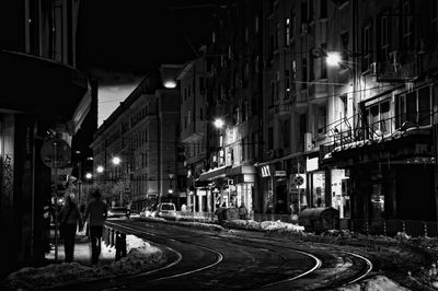Vehicles on road along buildings at night