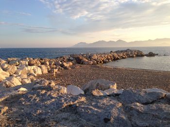 Rocks on beach against sky during sunset