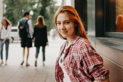 Portrait of smiling young woman standing on footpath