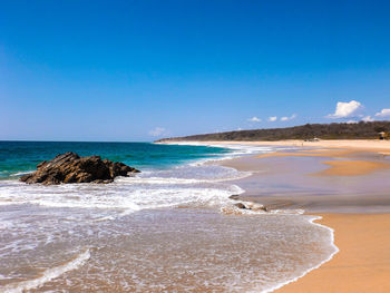 Scenic view of beach against clear blue sky