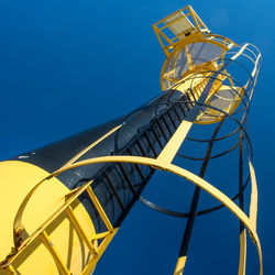 Low angle view of light tower against clear blue sky