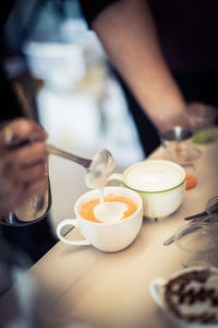 High angle view of barista mixing milk in drink at cafe