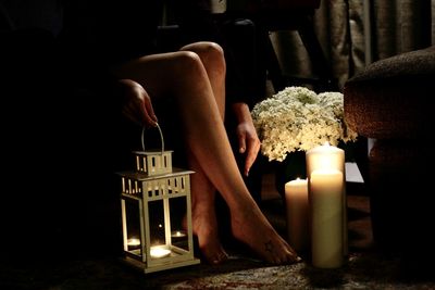Woman legs by illuminated candles on table