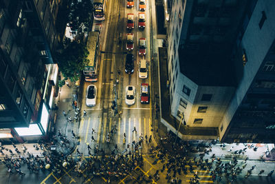 High angle view of crowd crossing city street by buildings at night