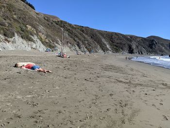 People on beach against mountain