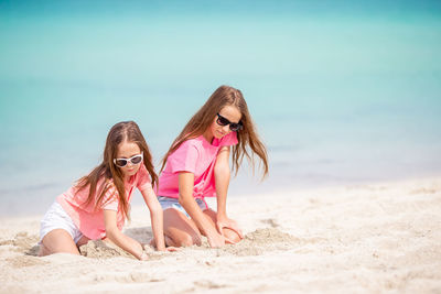 Sisters plying with sand on beach