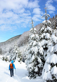 Rear view of backpack woman skiing at snowcapped mountain during winter