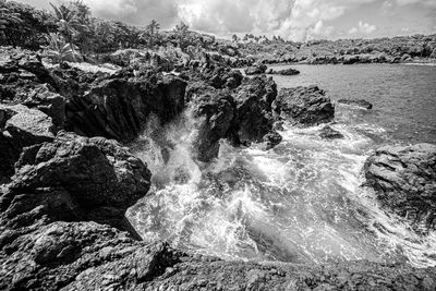 Scenic view of rocks in sea against sky