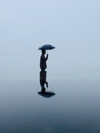 Man with umbrella standing in water