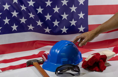 Cropped hand of person reaching for hardhat by work tools and american flag