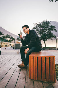 Side view of man using mobile phone while sitting in city