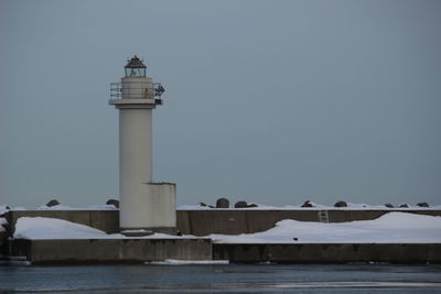 Lighthouse by sea against sky