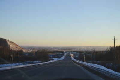 Road amidst trees against clear sky during winter