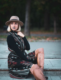 Portrait of woman wearing hat sitting outdoors