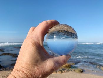 Close-up of hand holding sunglasses against clear sky