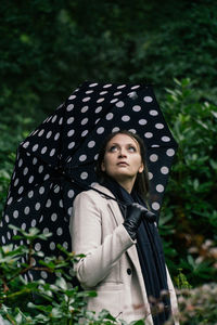 Portrait of young woman standing against trees