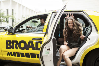 Playful female friends sitting in taxi