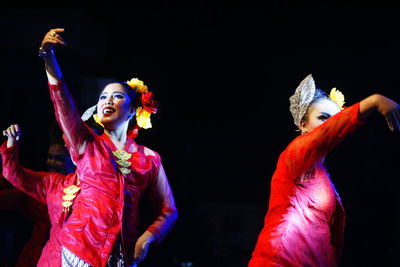 Young man dancing in traditional clothing against black background