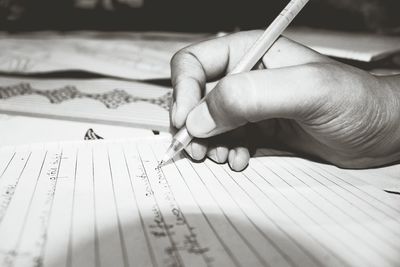 Close-up of cropped hand writing on book at home