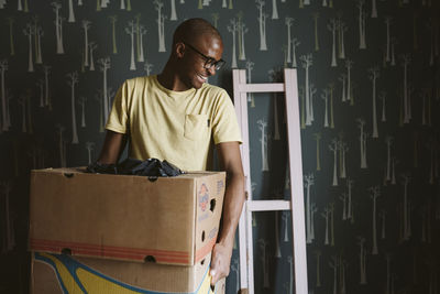 Smiling man carrying cardboard boxes