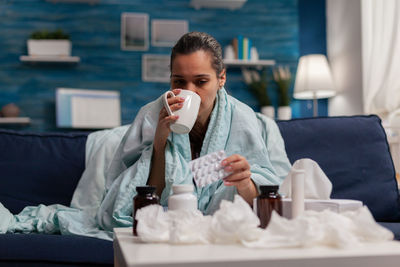 Ill woman taking medicine while sitting at home