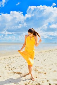 Young woman walking at beach against sky